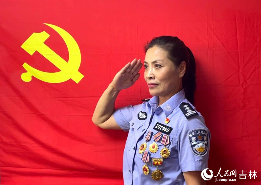 軍烈屬王永玲在黨旗下敬禮。人民網記者 李思玥攝