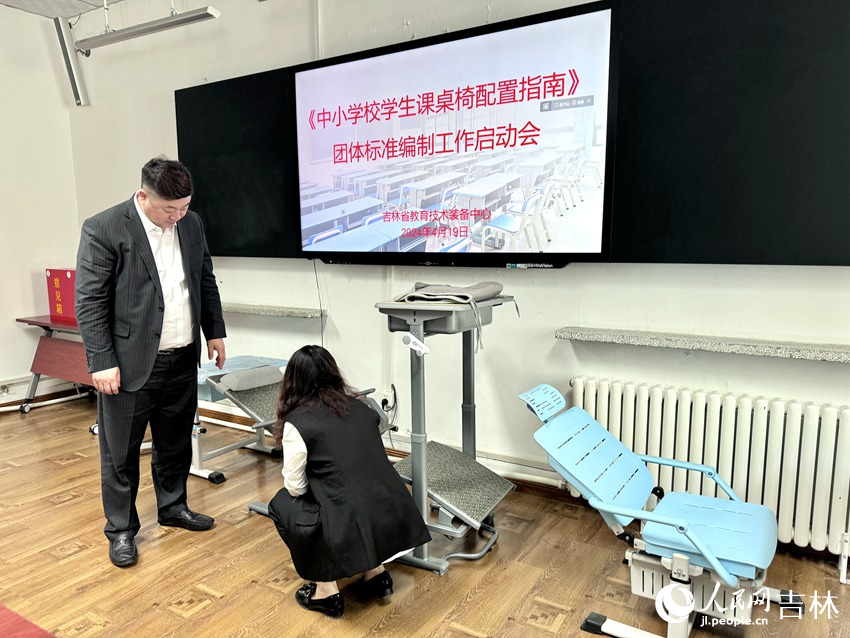 政協委員、課桌椅生產企業對市面上的課桌椅展開研究討論。人民網記者 李思玥攝