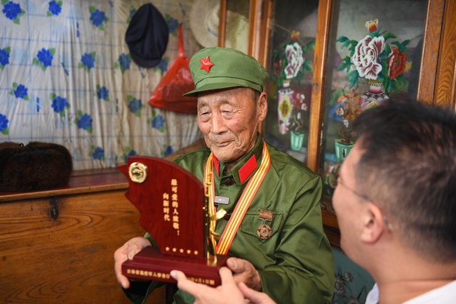 省退役軍人事務廳人員向老兵張俊財贈送榮譽激勵牌。