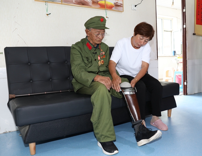 老兵王振余親屬幫助他佩戴假肢。