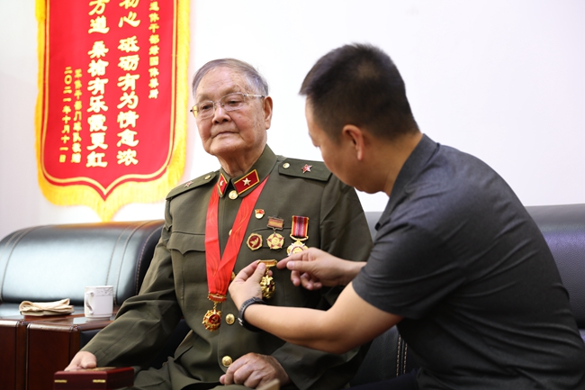 關愛老兵志愿者為老兵汪延開佩戴軍功章。