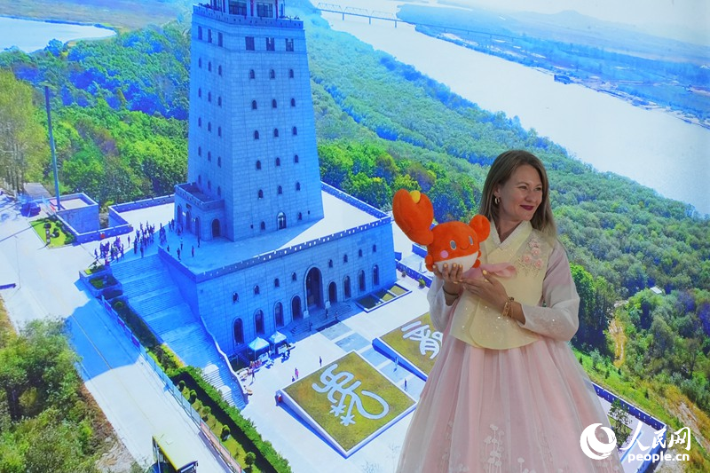 塔尼婭在延邊展館“一眼望三國”背景板前打卡拍照。人民網記者 李洋攝