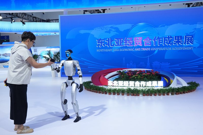 游客在東北亞經貿合作成果展上與機器人握手。人民網記者 李洋攝