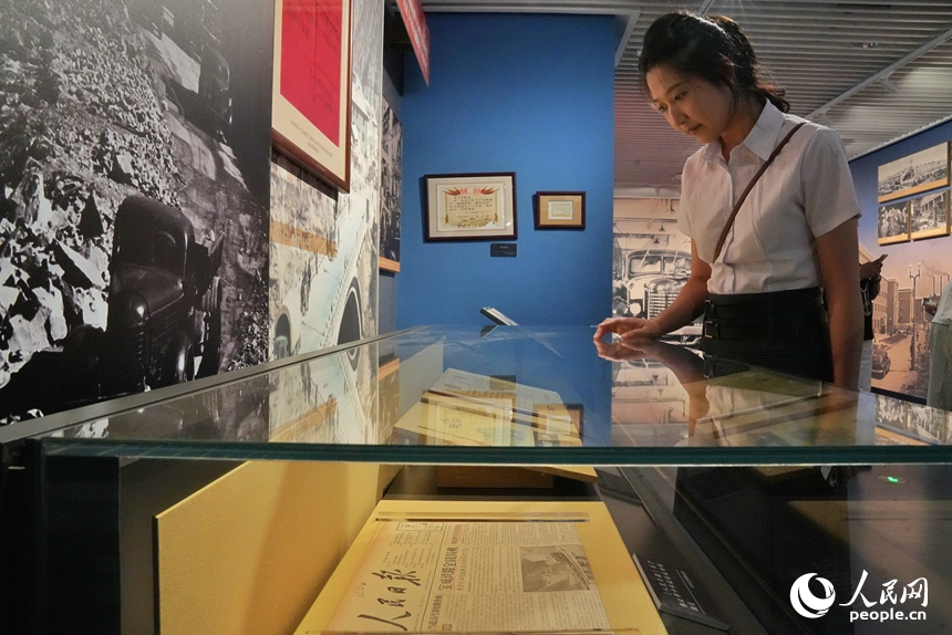 一名觀眾在展區內觀看1956年《人民日報》關于解放牌卡車試制成功的報道。人民網記者 李洋攝