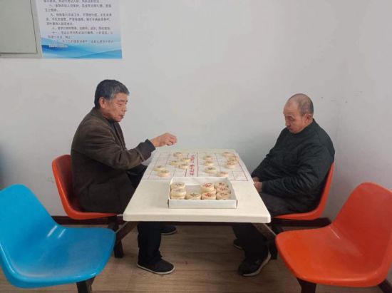 張學敬老人（圖左）在涿州市中心敬老院跟新認識的朋友下象棋。李大慶攝