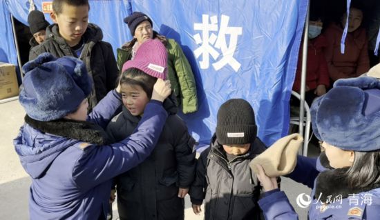 2023年12月21日，青海省海東市消防救援支隊的隊員們正在為受災的小朋友穿戴御寒衣物。人民網記者 劉沛然攝
